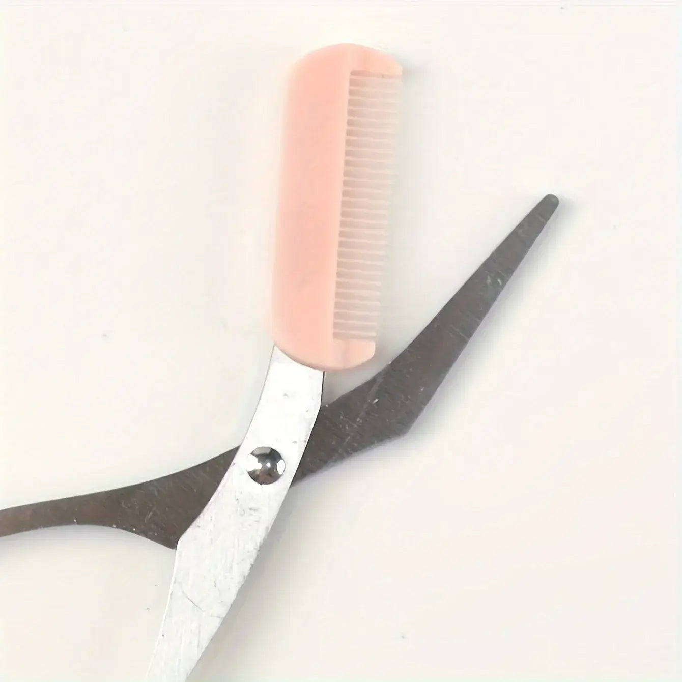 Frost Glow Cosmetics pink eyebrow scissors with built-in comb. Stainless steel, precise grooming tool for shaping perfect brows.
