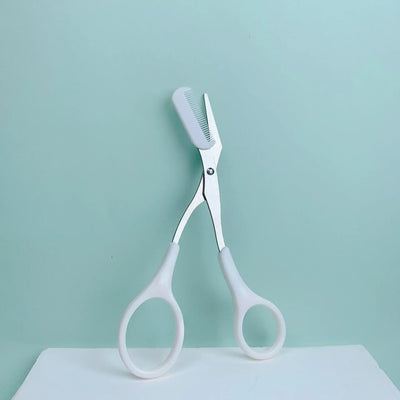 Frost Glow Cosmetics pink eyebrow scissors with built-in comb. Stainless steel, precise grooming tool for shaping perfect brows.