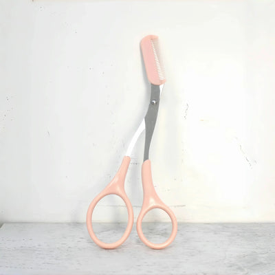 Frost Glow Cosmetics pink eyebrow scissors with built-in comb. Stainless steel, precise grooming tool for shaping perfect brows.