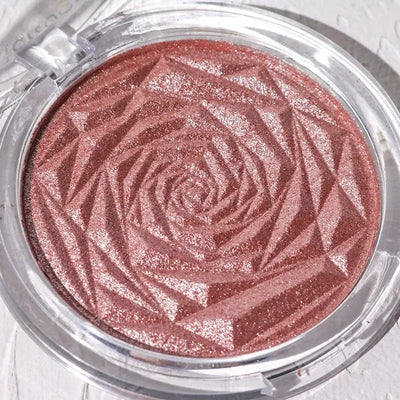 Frost Glow Cosmetics Diamond Glow highlighter showcased on skin and model, featuring shimmering rose-patterned design.