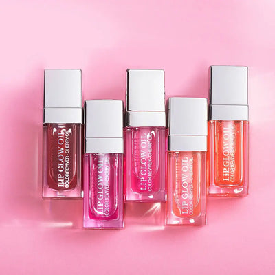 Frost Glow Cosmetics lip oil balms in pink, coral, and berry shades on a pink background.